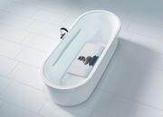 Vogelperspektive auf eine weiße Badewanne mit einer Wanneneinlage, die ein Bild von gestapelten Steinen zeigt.