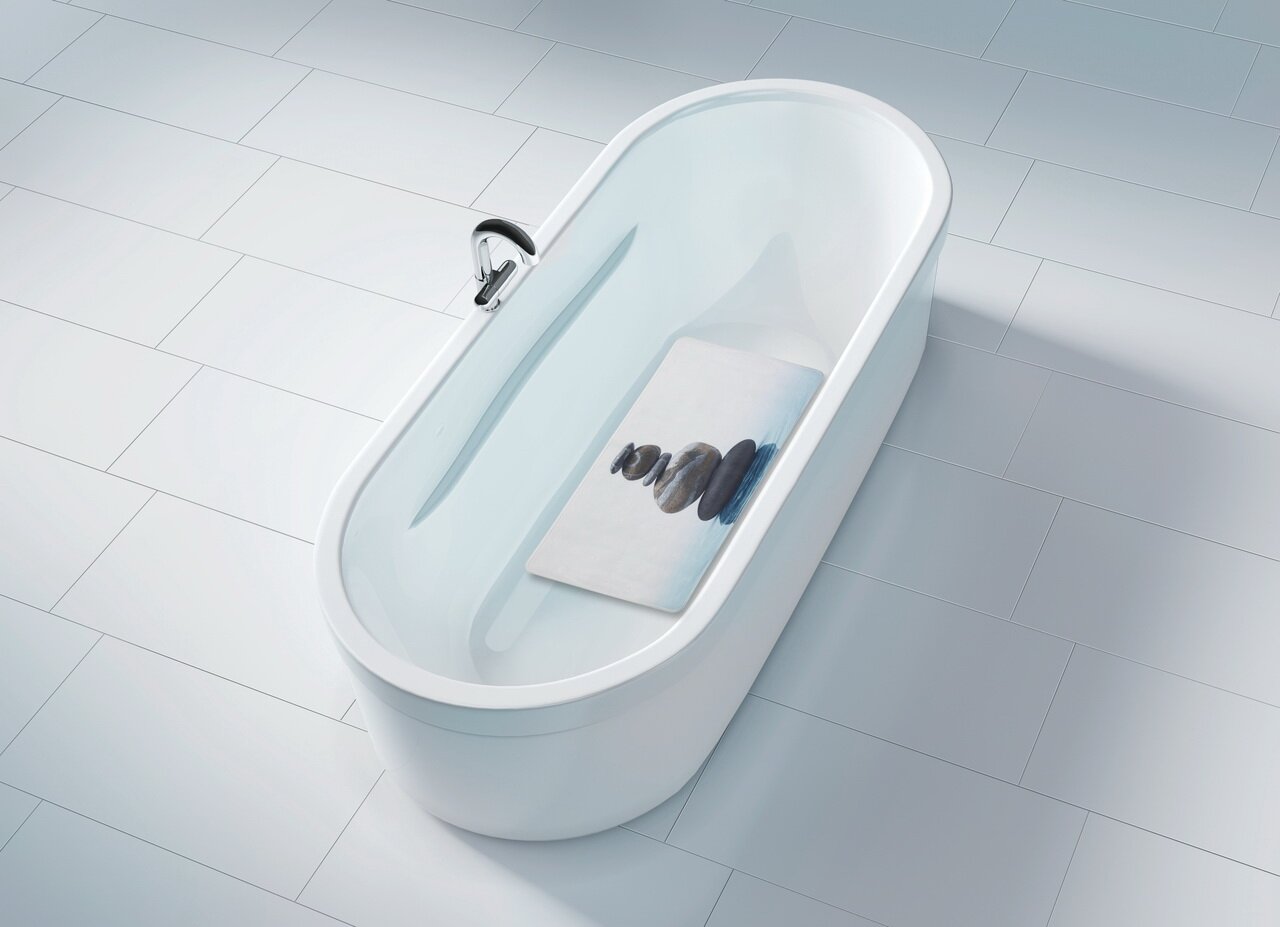 Vogelperspektive auf eine weiße Badewanne mit einer Wanneneinlage, die ein Bild von gestapelten Steinen zeigt.