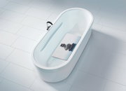 Vogelperspektive auf eine weiße Badewanne mit einer Wanneneinlage, die ein Bild von gestapelten Steinen zeigt.