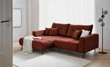 Rote Ecksofa mit Ottomane links, dekoriert mit Kissen und Decke, in einem modernen Wohnzimmer mit hellem Holzboden und Stehlampe, Perspektive von vorne links.