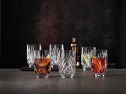 Sechs elegante Kristallgläser mit facettiertem Design, gefüllt mit bunten Getränken, auf einer dunklen Oberfläche vor einem dunklen Hintergrund, aus einer leicht erhöhten Perspektive fotografiert.