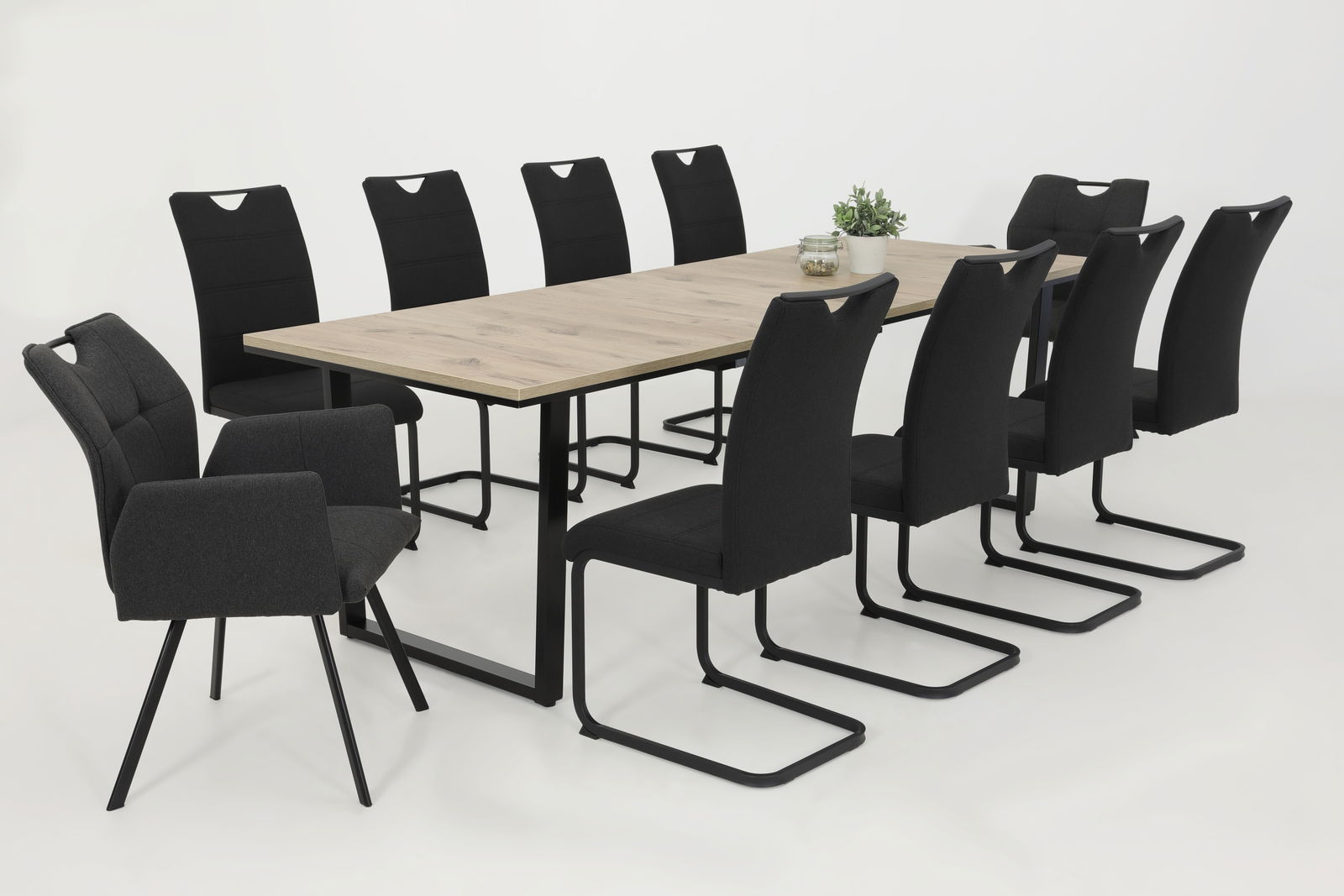 Esszimmer mit einem langen Holztisch und acht schwarzen Schwingstühlen, seitliche Perspektive