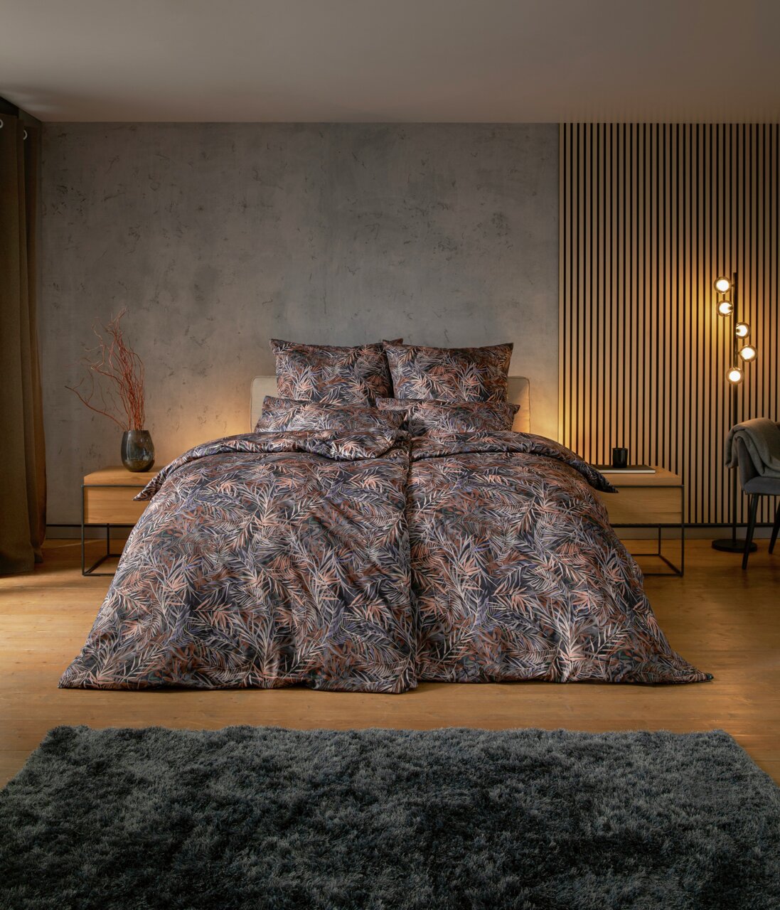 Bettwäsche-Set mit tropischem Blattmuster in einem modernen Schlafzimmer, frontal aufgenommen.