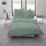 Grüne Bettwäsche mit geometrischem Muster auf einem Bett in einem modernen Schlafzimmer, seitliche Perspektive