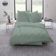 Grüne Bettwäsche mit geometrischem Muster auf einem Bett in einem modernen Schlafzimmer, seitliche Perspektive