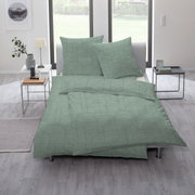 Grüne Bettwäsche mit geometrischem Muster auf einem Bett in einem modernen Schlafzimmer, seitliche Perspektive