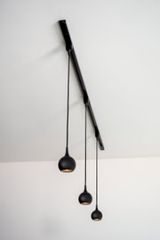 Dreiflammige schwarze Pendelleuchte FAVORI, von unten fotografiert, mit kugelförmigen Lampenschirmen an einer Schiene hängend.