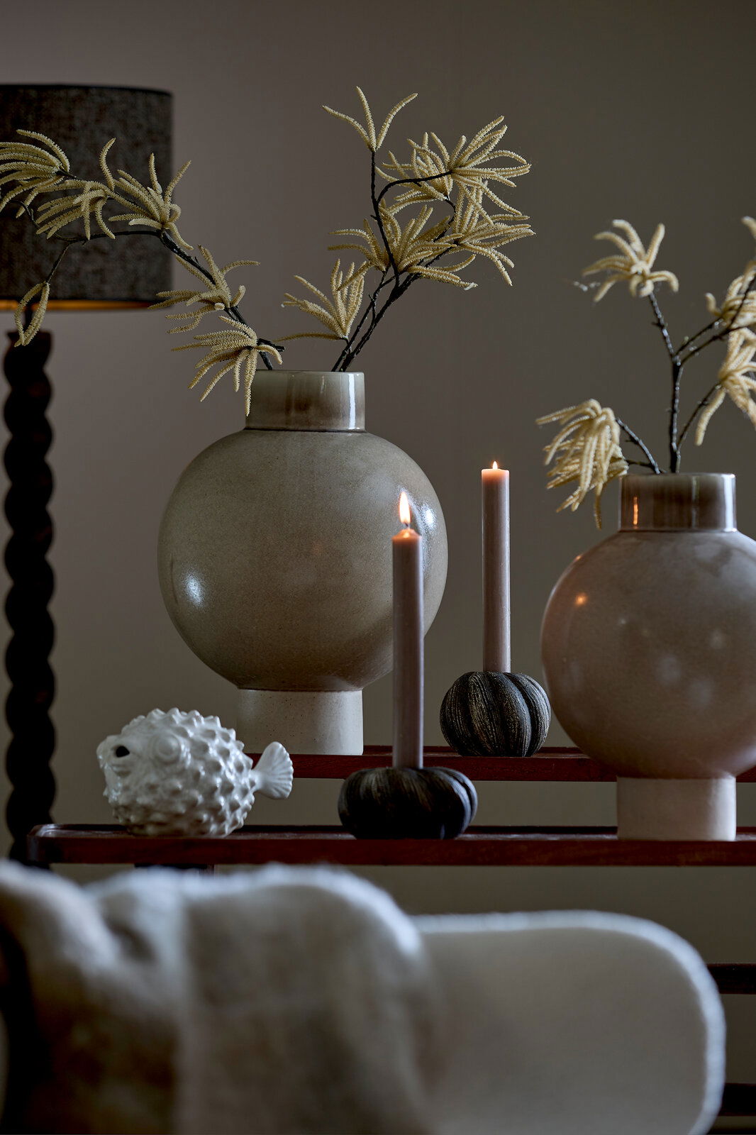 Light&Living Ornament FISH 11,5cm Dekorative Szene mit zwei großen, runden Vasen mit künstlichen Zweigen, zwei brennenden Kerzen in Haltern und einem weißen Fisch-Ornament. Die Perspektive ist frontal auf die Anordnung gerichtet.