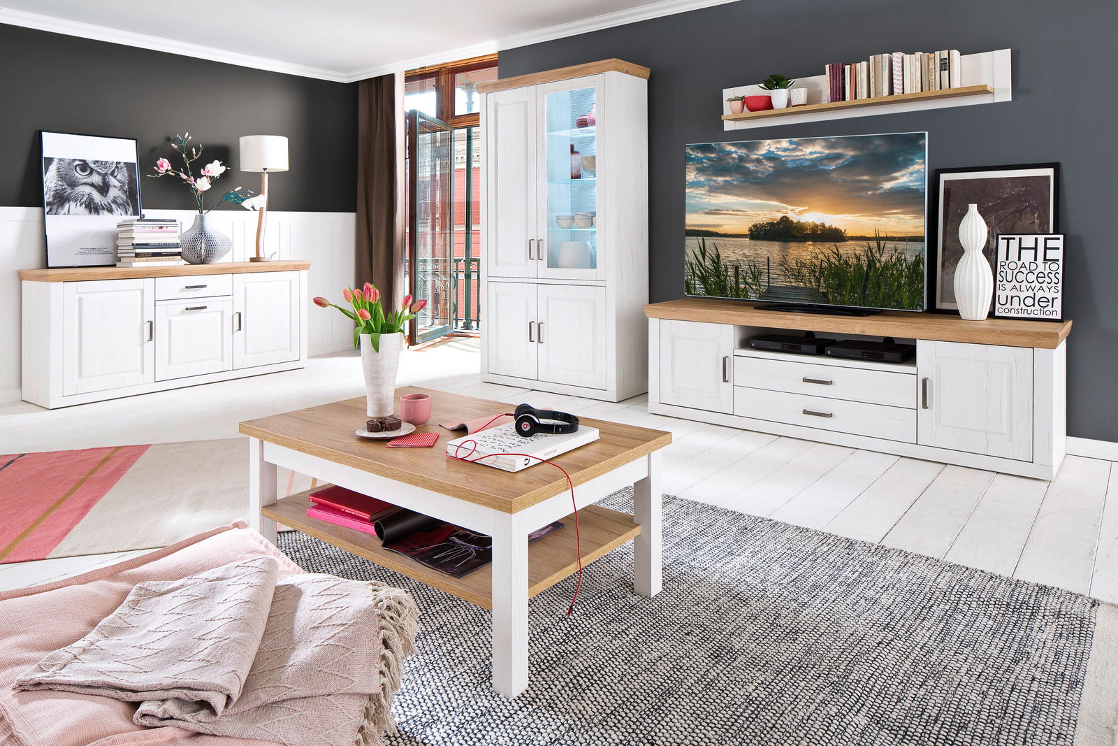 Wohnzimmer mit moderner Wandkombination in Weiß und Holzoptik, bestehend aus Sideboard, Highboard, TV-Lowboard und Wandregal, aus der Perspektive des Wohnzimmers fotografiert.