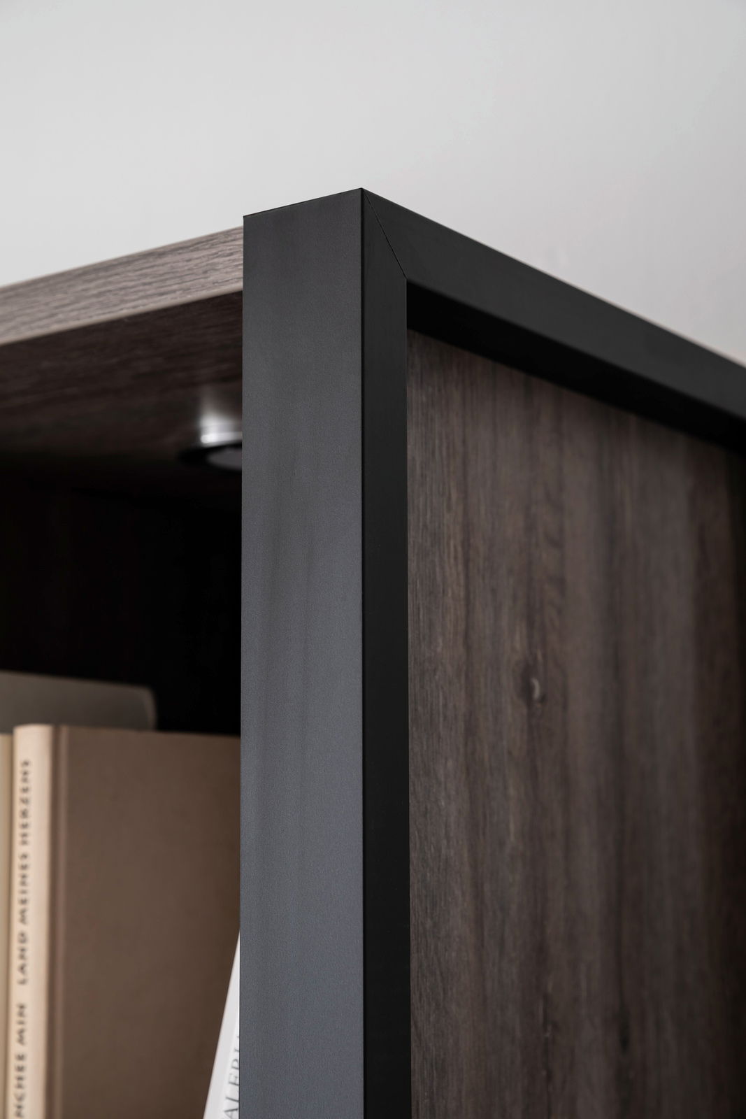 Nahaufnahme eines modernen Highboards mit dunklem Holz und schwarzem Metallrahmen, Perspektive von der Seite.