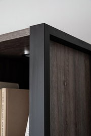 Nahaufnahme eines modernen Highboards mit dunklem Holz und schwarzem Metallrahmen, Perspektive von der Seite.