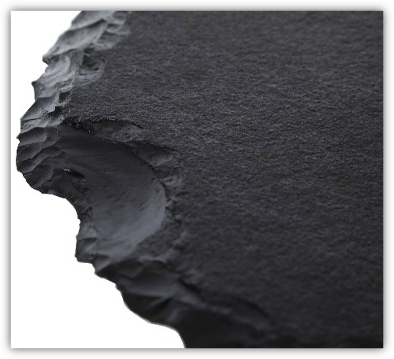 Nahaufnahme einer schwarzen, strukturierten Tischplatte mit unregelmäßigen Kanten, perspektivisch von der Seite aufgenommen.