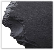 Close-up van een zwart, gestructureerd tafelblad met onregelmatige randen, vanuit een zijdelingse hoek gefotografeerd.