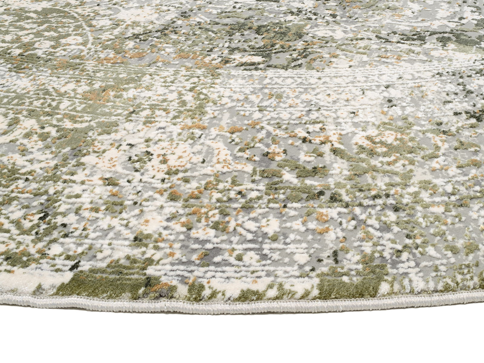 Nahaufnahme eines Designer Teppichs mit abstraktem Muster in Grün- und Grautönen, von der Seite fotografiert.