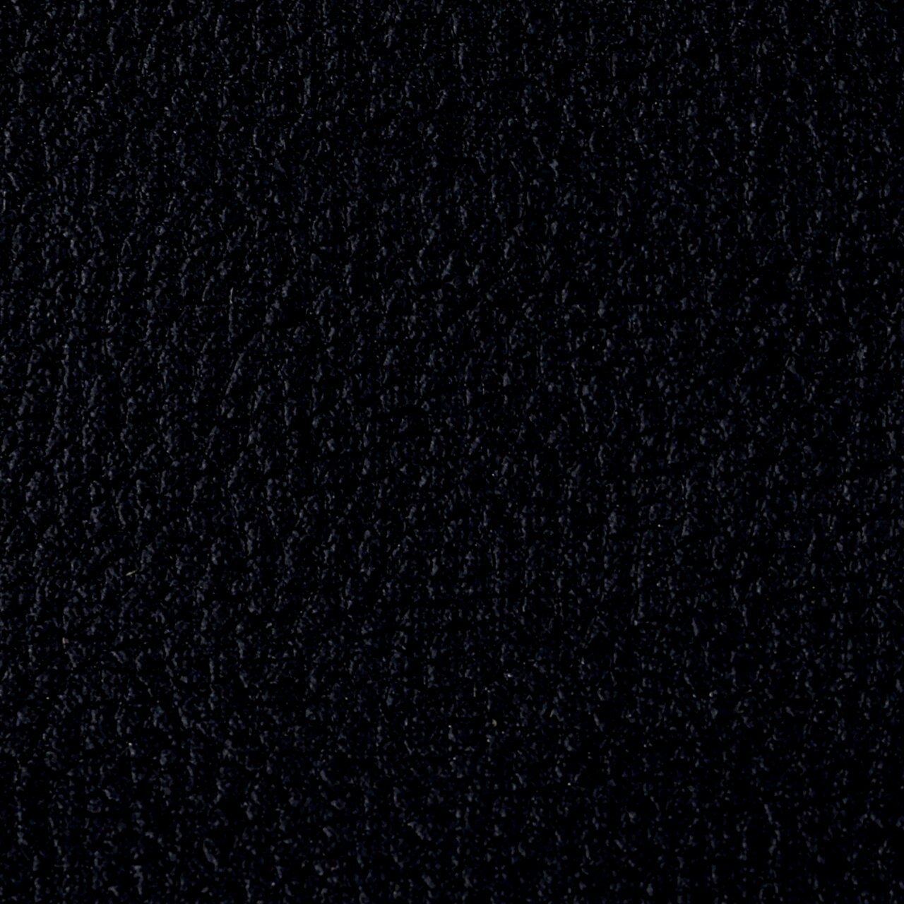 Nahaufnahme der schwarzen Lederstruktur eines Armlehnstuhls