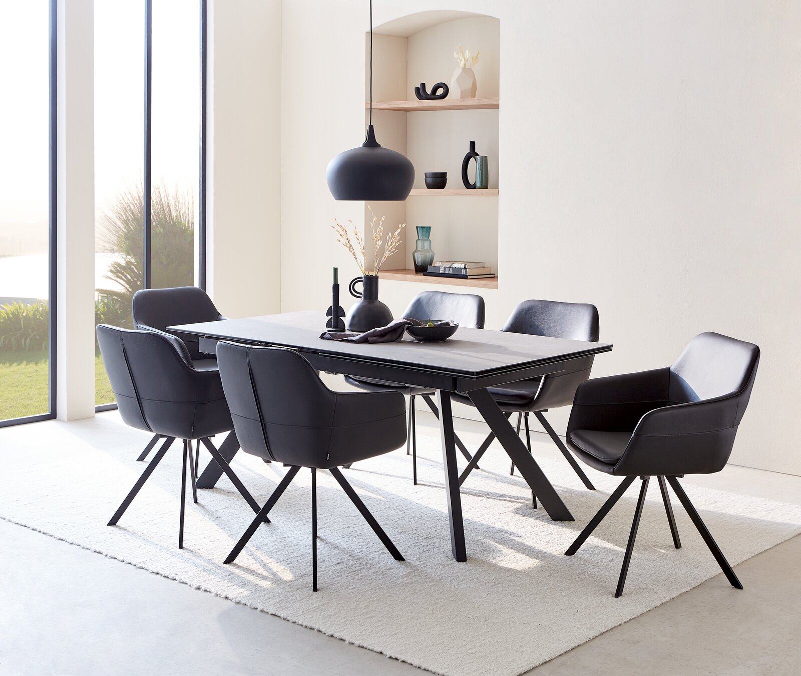 Esszimmer mit modernem Tisch und sechs schwarzen Sesseln, seitliche Perspektive