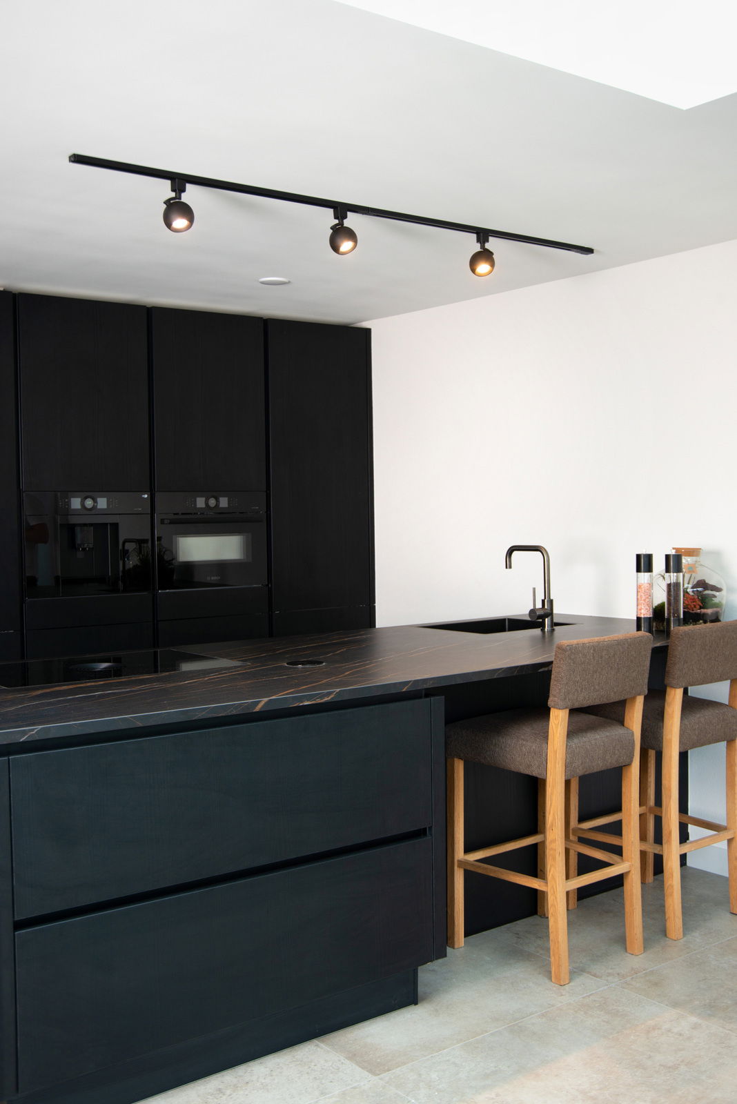 Schwarzer Strahler FAVORI TRACK von Lucide Leuchten, montiert an der Decke einer modernen Küche, aus seitlicher Perspektive fotografiert.