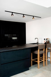 Zwarte spot FAVORI TRACK van Lucide Leuchten, gemonteerd aan het plafond van een moderne keuken, gefotografeerd vanuit een zijdelingse hoek.