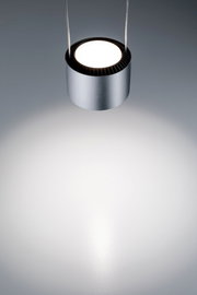 Moderne, zylindrische Hängeleuchte in silberner Farbe, von oben fotografiert, mit hellem Lichtstrahl auf einer grauen Oberfläche.