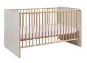 Modernes Babybett/Gitterbett aus hellem Holz mit weißen Seitenteilen und Matratze, freigestellt vor weißem Hintergrund, in schräger Frontansicht von vorn links