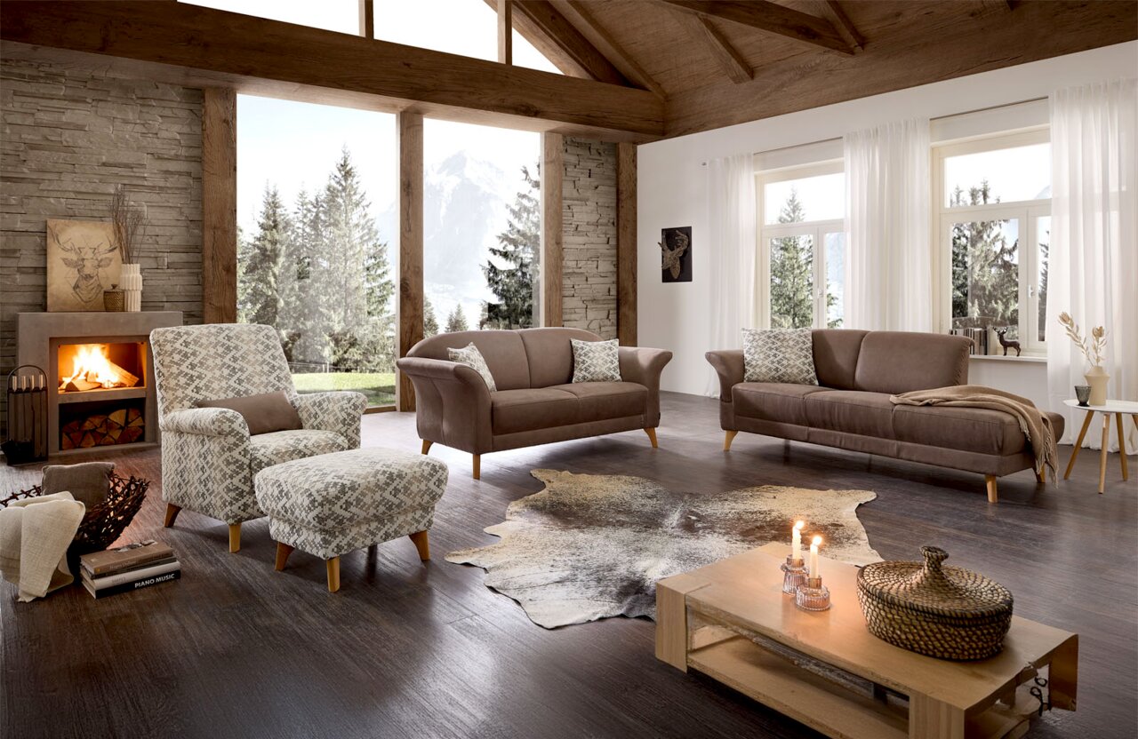 Gezellige woonkamer met fauteuil en recamier in een moderne, rustieke omgeving met open haard en uitzicht op de bergen.