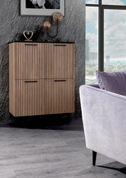 Modernes Highboard mit vertikalen Holzlamellen, seitliche Perspektive, dekoriert mit Skulpturen und Lampen, vor einer grauen Wand.