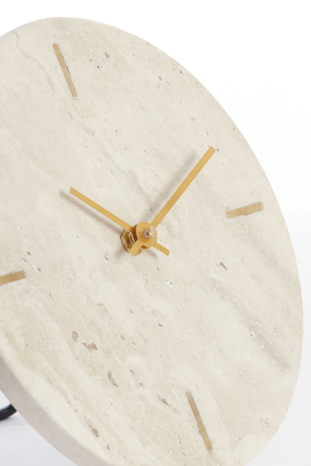 Nahaufnahme einer eleganten Wanduhr aus hellem Naturstein mit goldenen Zeigern und minimalistischen Markierungen, seitliche Perspektive.
