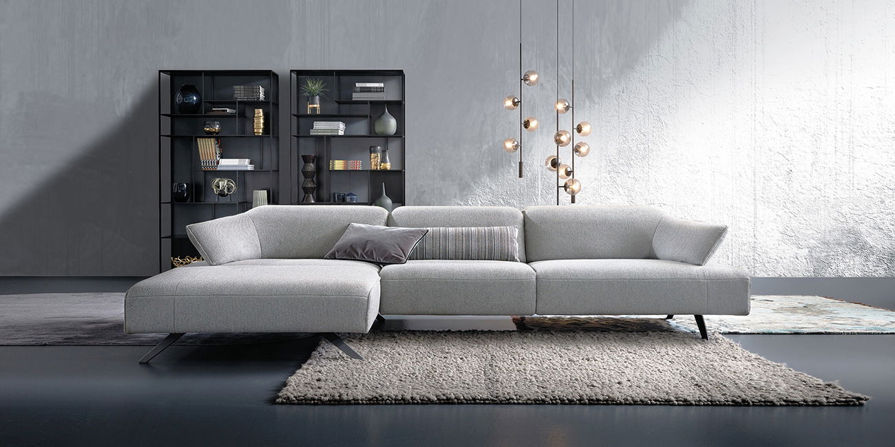 „Ein großes, helles Sofa steht vor zwei dunklen Regalen