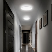 Moderne ronde LED-plafondlampen die een gang verlichten, gezien in perspectief van onderaf richting het einde van de hal