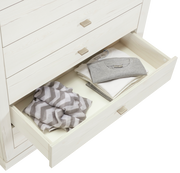 Weiße Kommode CAMRON mit offener Schublade, gefüllt mit gefalteter Kleidung, aus der Vogelperspektive.