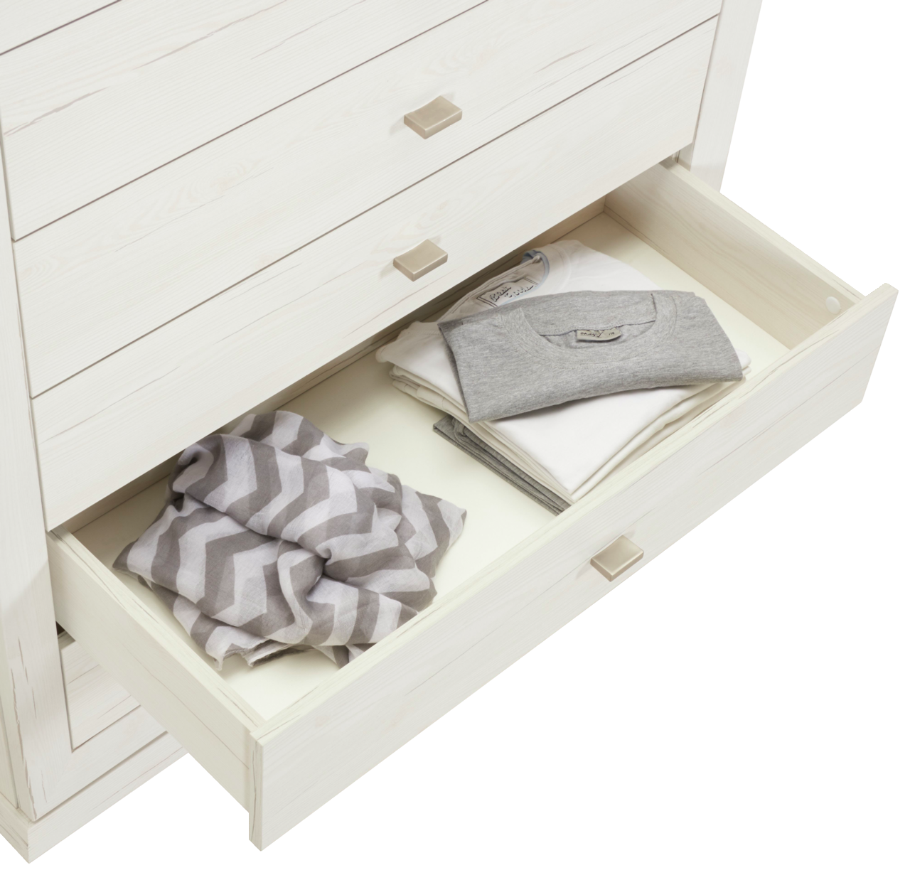 Weiße Kommode CAMRON mit offener Schublade, gefüllt mit gefalteter Kleidung, aus der Vogelperspektive.