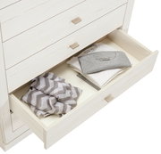 Weiße Kommode CAMRON mit offener Schublade, gefüllt mit gefalteter Kleidung, aus der Vogelperspektive.