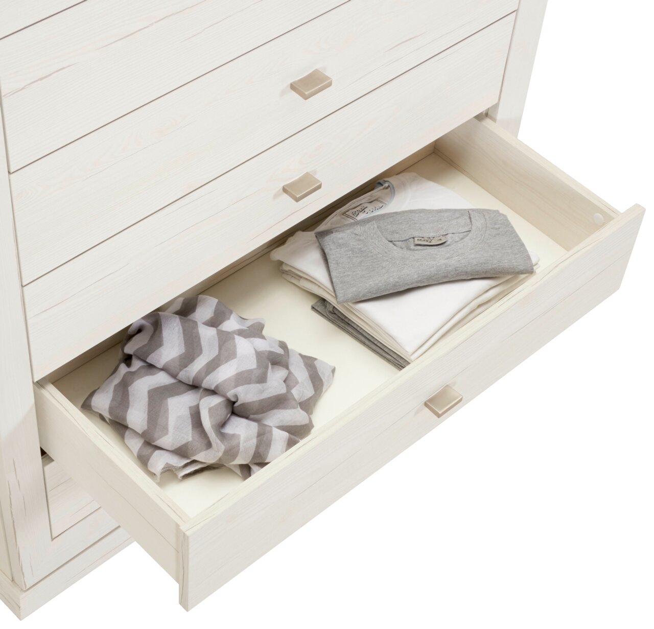 Weiße Kommode CAMRON mit offener Schublade, gefüllt mit gefalteter Kleidung, aus der Vogelperspektive.