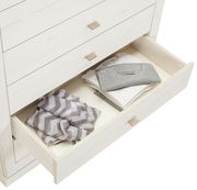 Weiße Kommode CAMRON mit offener Schublade, gefüllt mit gefalteter Kleidung, aus der Vogelperspektive.