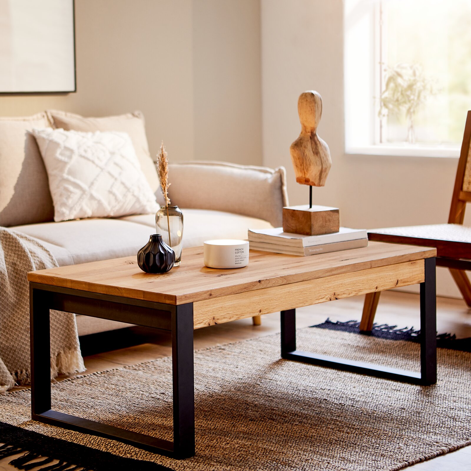 Moderner Couchtisch aus Holz mit schwarzem Metallgestell in einem gemütlichen Wohnzimmer, seitliche Perspektive.