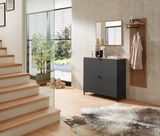 Moderner Eingangsbereich mit einem schwarzen Hänge-Schuhschrank, einem schmalen Spiegel und einem Garderobenpaneel aus Holz. Perspektive von der Seite mit Blick auf die Treppe und den Außenbereich.
