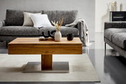 Moderner Couchtisch aus Holz mit Metallfuß, dekoriert mit Vasen und Tassen, in einem stilvollen Wohnzimmer mit grauen Sofas, Frontalansicht.