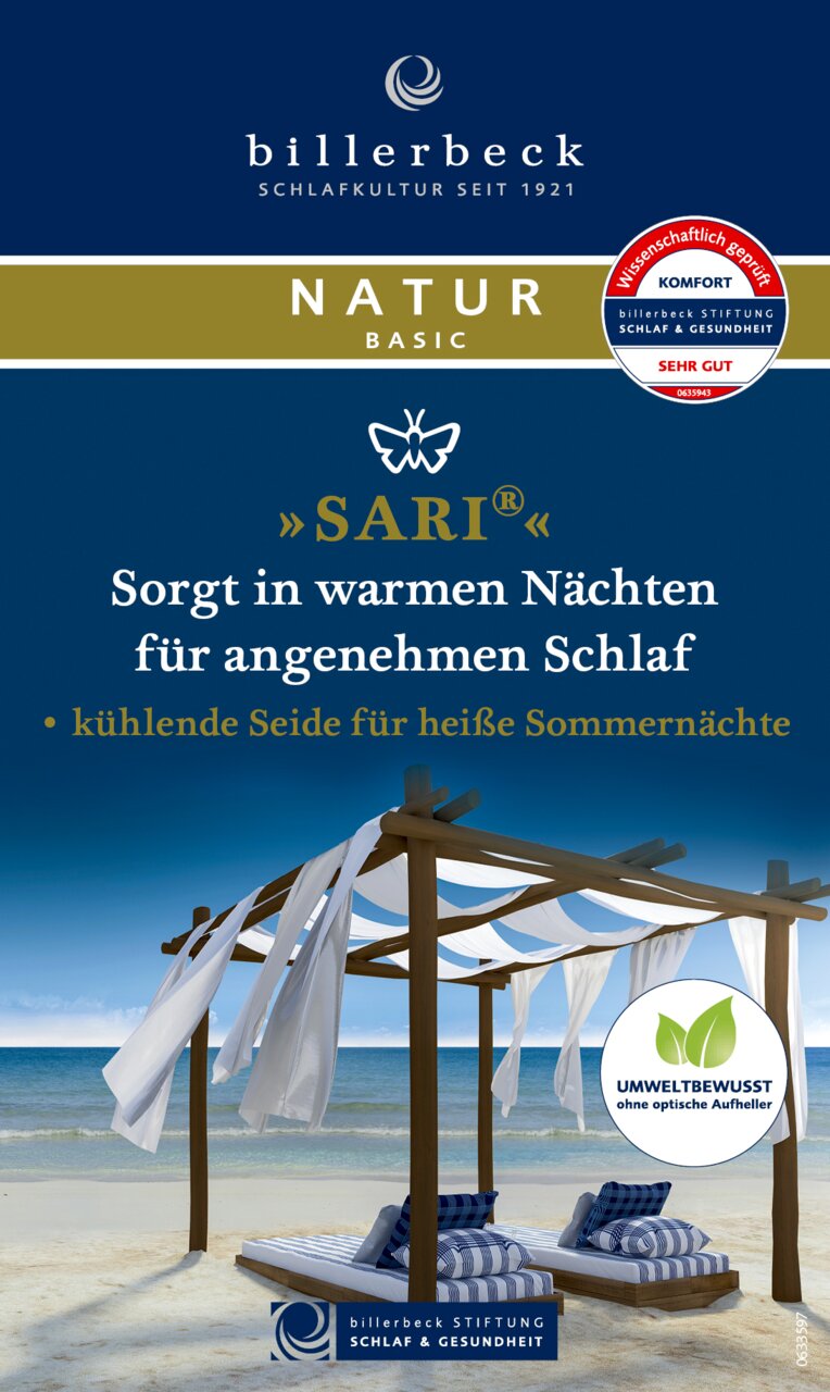 Een blik op een Billerbeck Superlight Sari-deken van wildzijde, gepresenteerd in een strandomgeving onder een houten paviljoen met wapperende witte doeken, ideaal voor warme zomernachten.