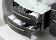 Moderner Badblock mit zwei geöffneten Schubladen, gefüllt mit Handtüchern und Pflegeprodukten, aus der Vogelperspektive fotografiert.