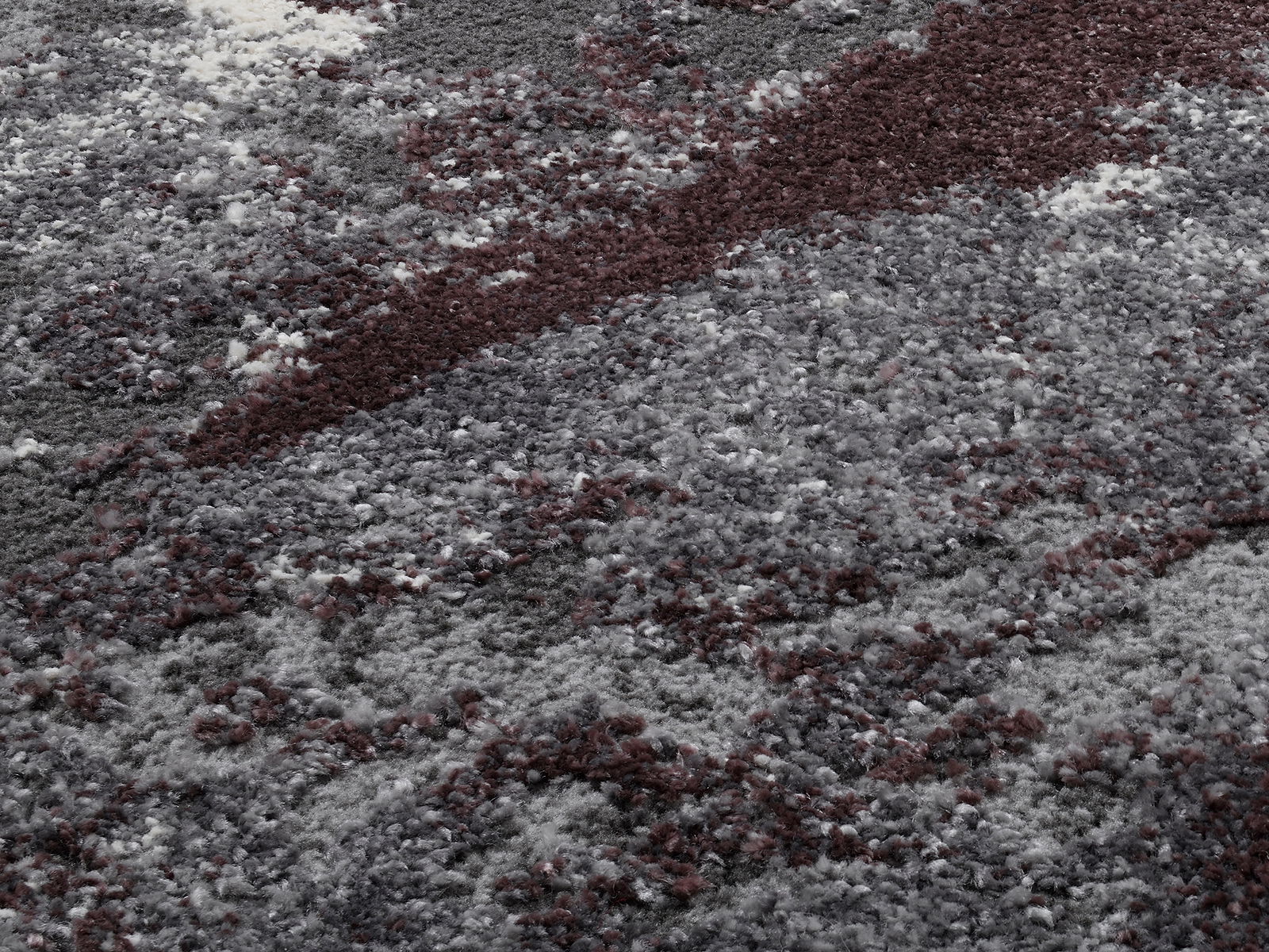 Nahaufnahme eines Designer Teppichs mit grauen und weinroten Mustern, von oben betrachtet.