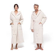 Zwei Personen in cremefarbenen Kapuzenmänteln, frontal fotografiert, mit Taschen und Gürtel.