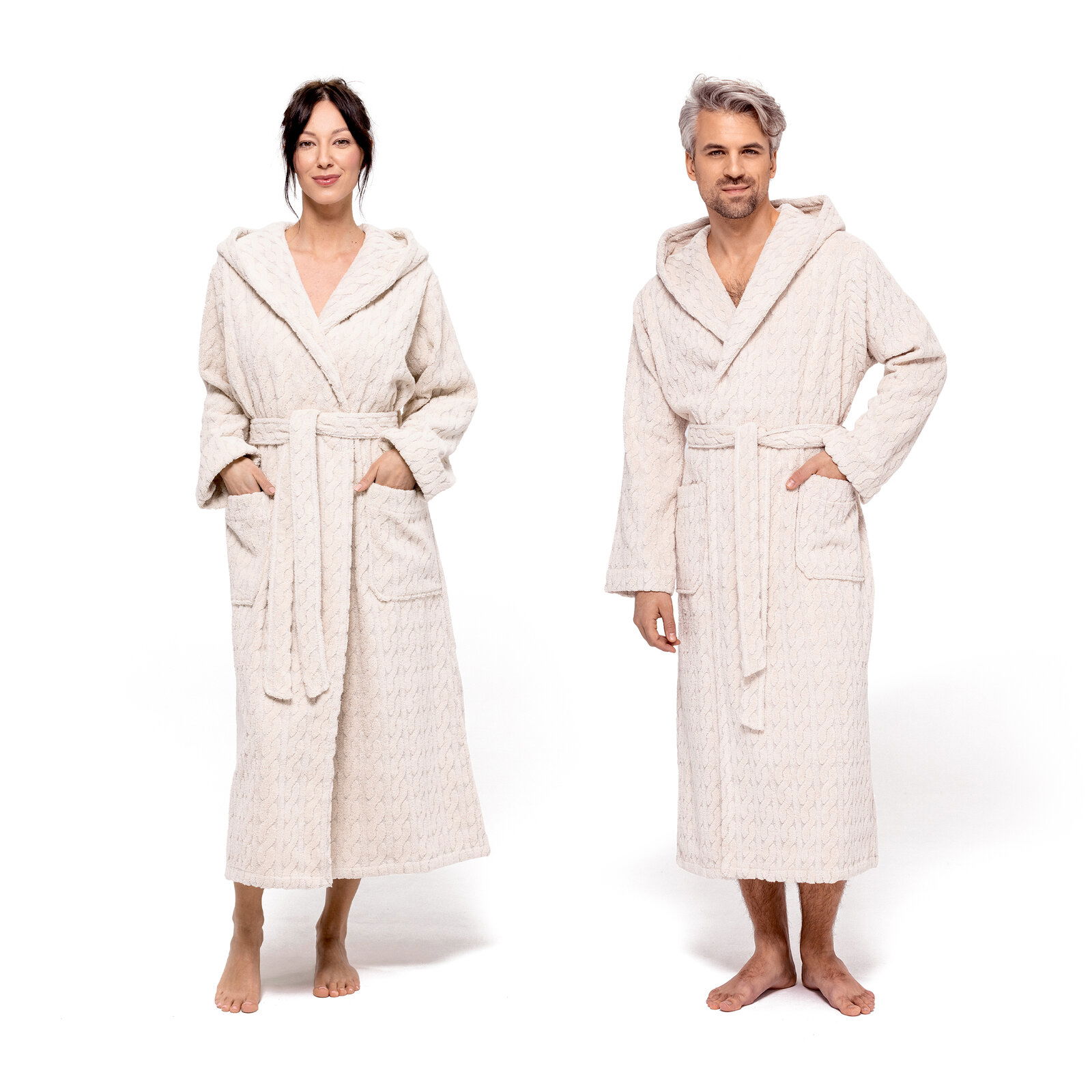 Zwei Personen in cremefarbenen Kapuzenmänteln, frontal fotografiert, mit Taschen und Gürtel.