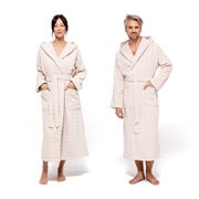 Zwei Personen in cremefarbenen Kapuzenmänteln, frontal fotografiert, mit Taschen und Gürtel.