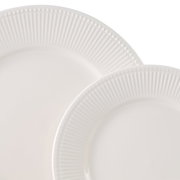 Nahaufnahme von zwei weißen Tellern mit geriffeltem Rand, übereinander gestapelt.