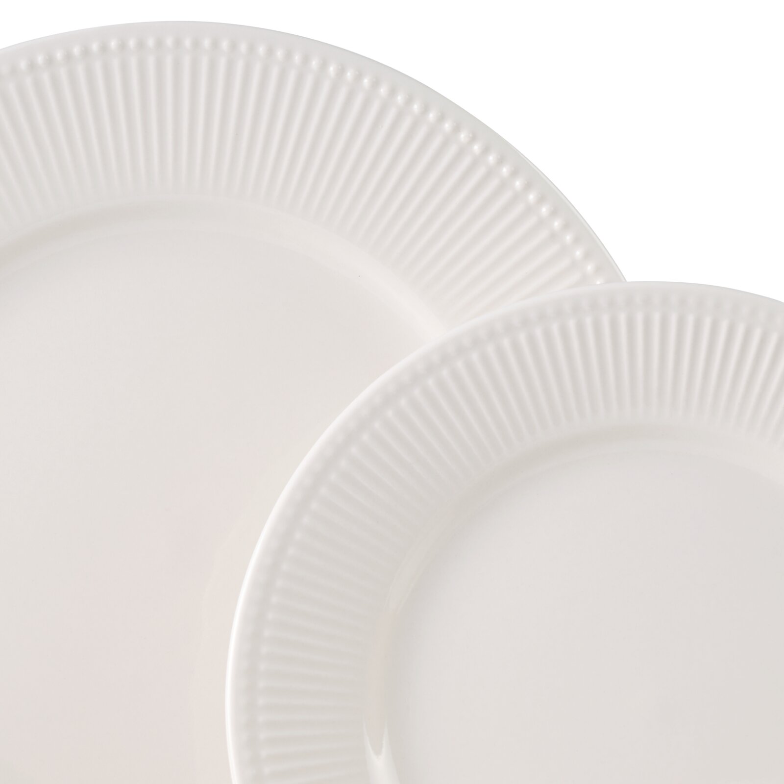 Nahaufnahme von zwei weißen Tellern mit geriffeltem Rand, übereinander gestapelt.