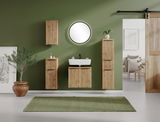 Moderner Waschbeckenunterschrank aus Holz mit vertikalen Lamellen, frontal vor einer grünen Wand montiert, umgeben von passenden Schränken und einem runden Spiegel.