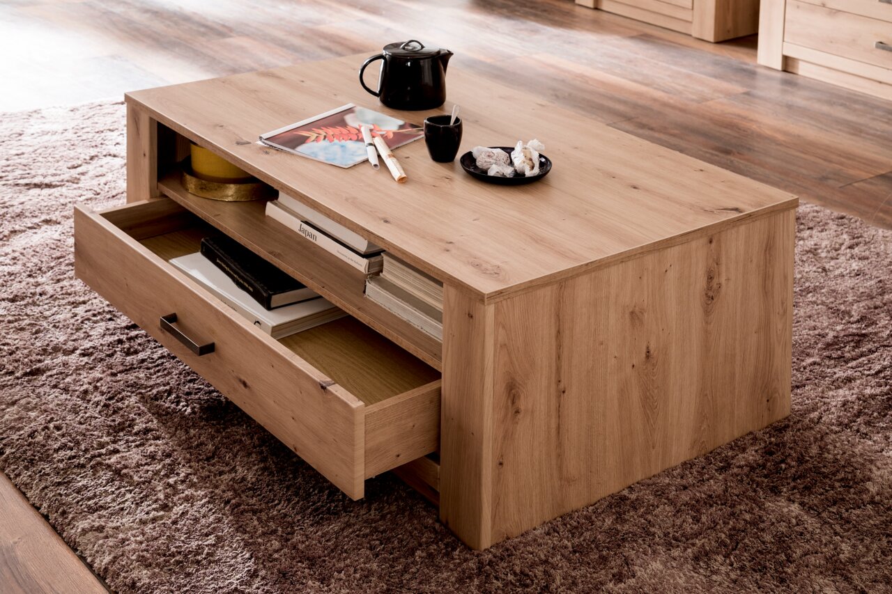 Moderner Couchtisch aus Holz mit Schubladen, von schräg oben fotografiert, auf einem Teppich stehend.