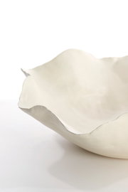 Nahaufnahme einer weißen, organisch geformten Schale mit unregelmäßigem Rand, seitliche Perspektive.