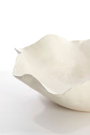 Nahaufnahme einer weißen, organisch geformten Schale mit unregelmäßigem Rand, seitliche Perspektive.