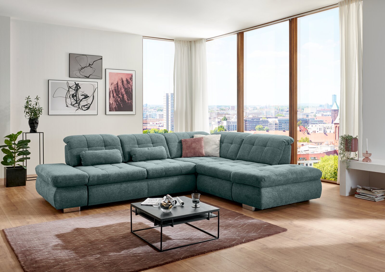 Großes türkisfarbenes, gepolstertes Ecksofa mit rechter Ottomane und gesteppten Sitzflächen im modernen Wohnzimmer vor bodentiefen Fenstern, Perspektive: frontal leicht von links.